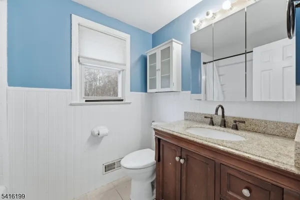 a bathroom with a granite countertop sink toilet and mirror