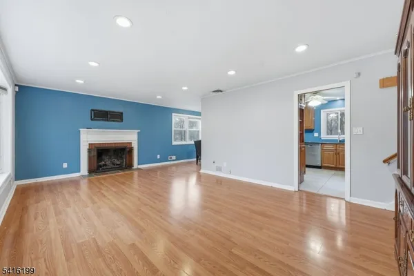 a view of an empty room with wooden floor fireplace and a window