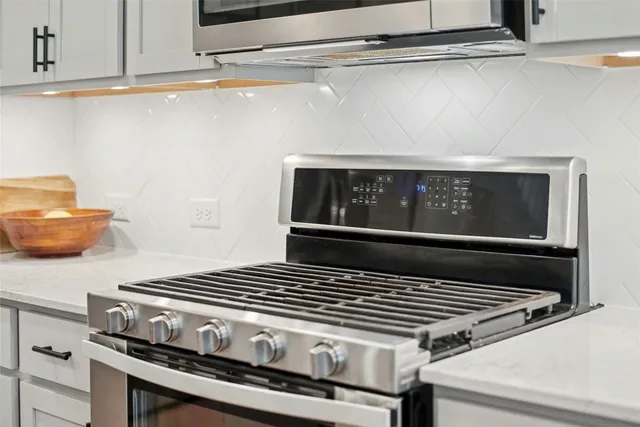 a kitchen with stainless steel appliances granite countertop a stove a refrigerator a stove a sink a dining table and chairs with wooden floor