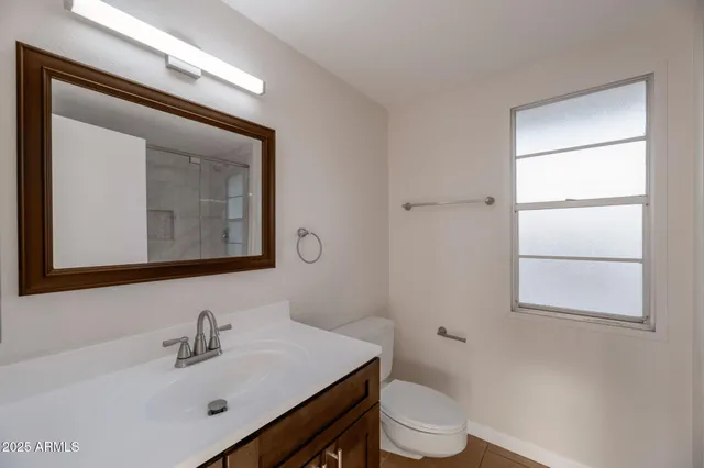a bathroom with a toilet sink vanity and mirror