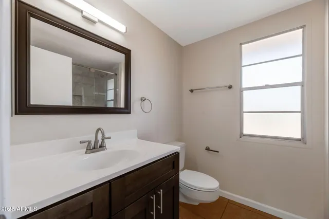 a bathroom with a toilet a sink a mirror and a window