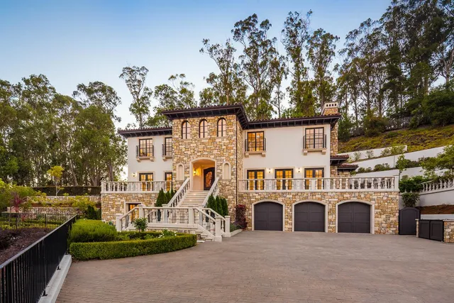 a view of a white house with a large tree