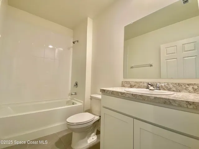 a bathroom with a granite countertop toilet sink and mirror