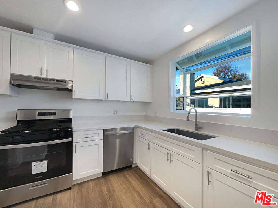 7944 Limerick Avenue Winnetka, CA 91306 - Photo 12 of 23 a kitchen with granite countertop white cabinets and black appliances