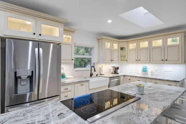 a kitchen with stainless steel appliances granite countertop a refrigerator a sink and white cabinets