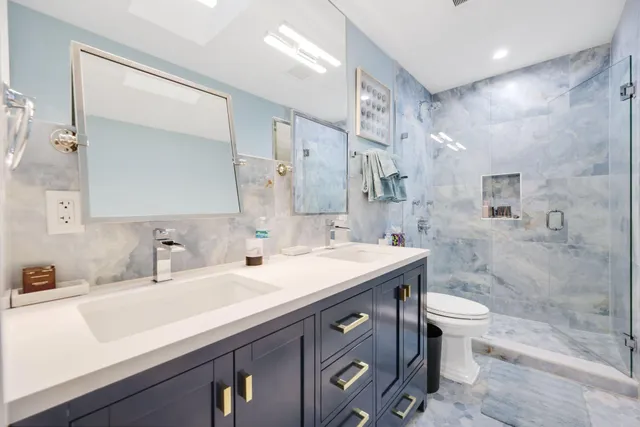 a bathroom with a sink a toilet a mirror and shower