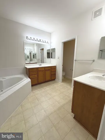 a large bathroom with a tub sink and mirror