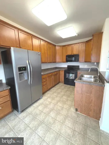 a kitchen with stainless steel appliances granite countertop a refrigerator a stove a sink a microwave and dining table