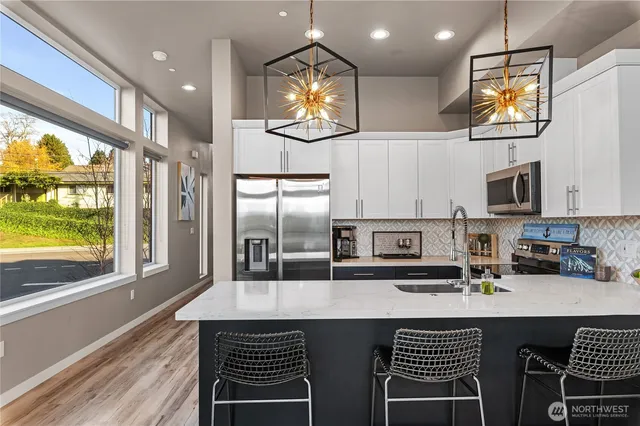 a kitchen with stainless steel appliances a sink a stove a microwave a refrigerator and cabinets