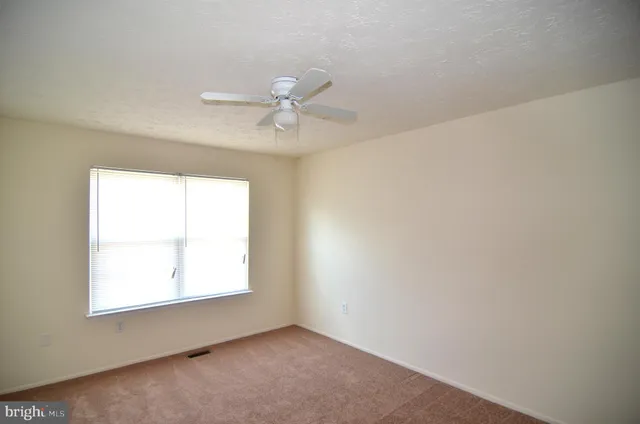 an empty room with a window and a fan