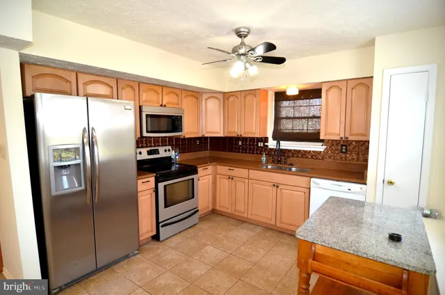 a kitchen with stainless steel appliances granite countertop a refrigerator a sink a stove and island