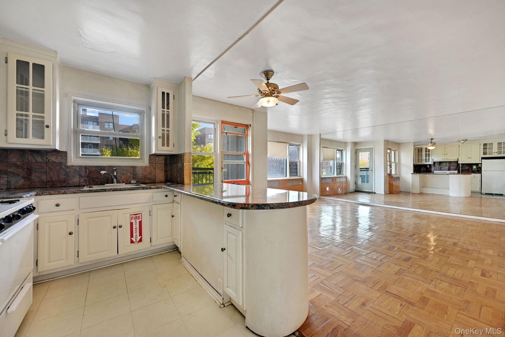 3131 Grand Concourse, Unit 3C Bronx, NY 10468 - Photo 16 of 27 a large white kitchen with cabinets a sink a window and stainless steel appliances