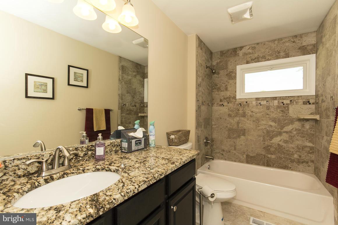 2100 Bayberry Road Edgewood, MD 21040 - Photo 22 of 30 a bathroom with a granite countertop sink a toilet a mirror a bathtub and shower