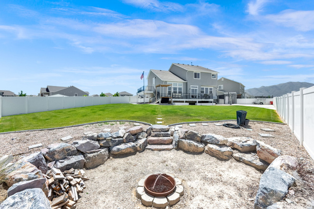 1857 Thunder Gulch Road Eagle Mountain, UT 84005 - Photo 39 of 50 Expansive backyard featuring a rock-lined fire pit area, an upper-level lawn, and a white privacy fence