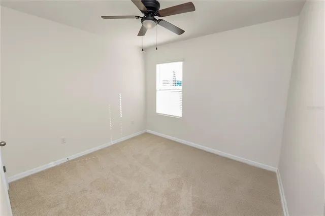 an empty room with a window and a fan