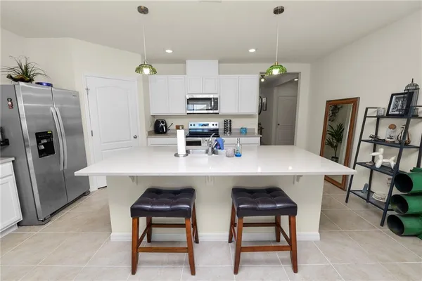 a kitchen with stainless steel appliances a dining table chairs refrigerator and microwave