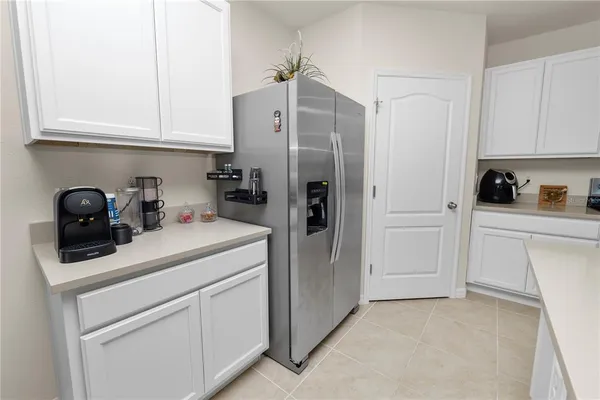 a kitchen with white cabinets and refrigerator
