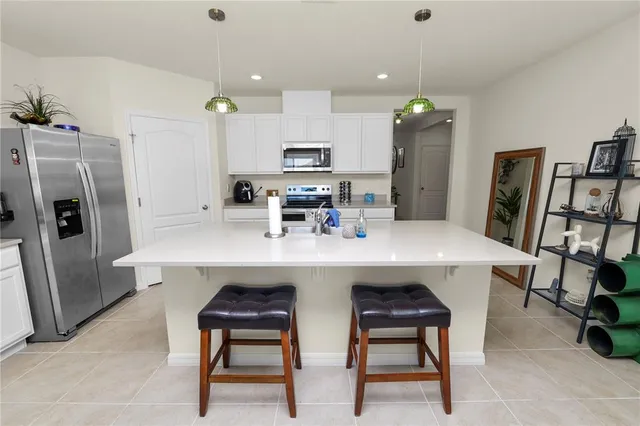 a kitchen with stainless steel appliances a dining table chairs refrigerator and microwave