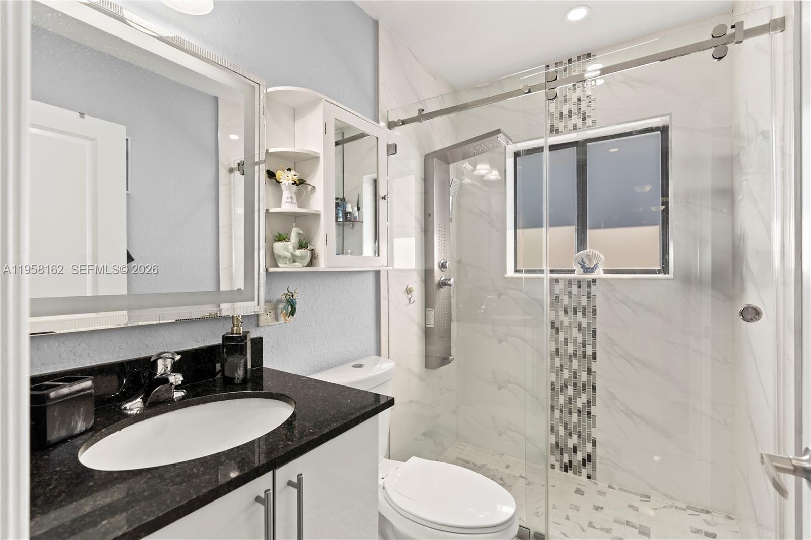 3281 Southwest 145th Avenue Miami, FL 33175 - Photo 51 of 56 a bathroom with a granite countertop sink toilet a mirror a shower and a mirror