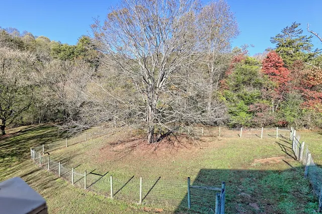 an empty room with a chandelier fan and windows