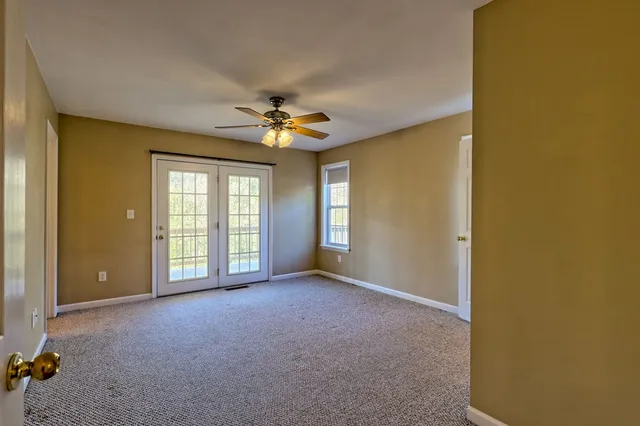 an empty room with windows and fan