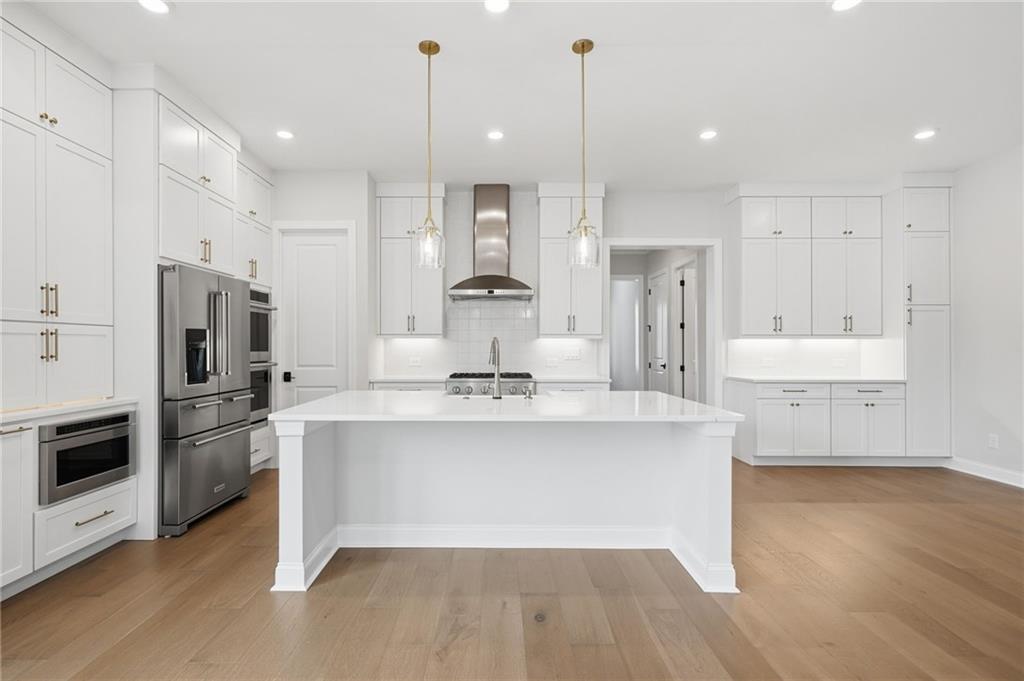 250 Idylwilde Way Canton, GA 30115 - Photo 19 of 59 a large kitchen with stainless steel appliances kitchen island granite countertop a stove a sink a refrigerator and white cabinets with wooden floor