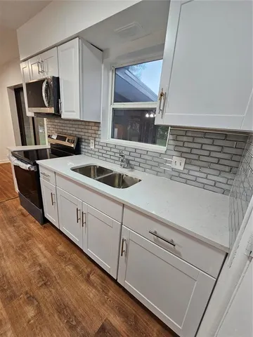 a kitchen with stainless steel appliances granite countertop a sink dishwasher stove and microwave with wooden floor