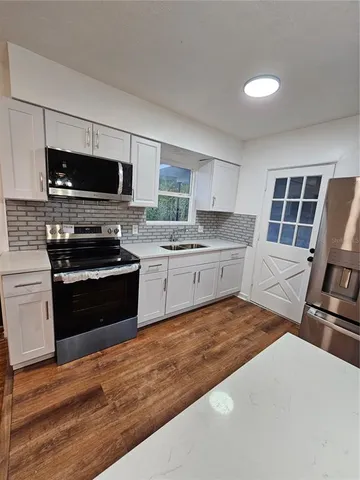 a large white kitchen with a stove a sink dishwasher and a refrigerator
