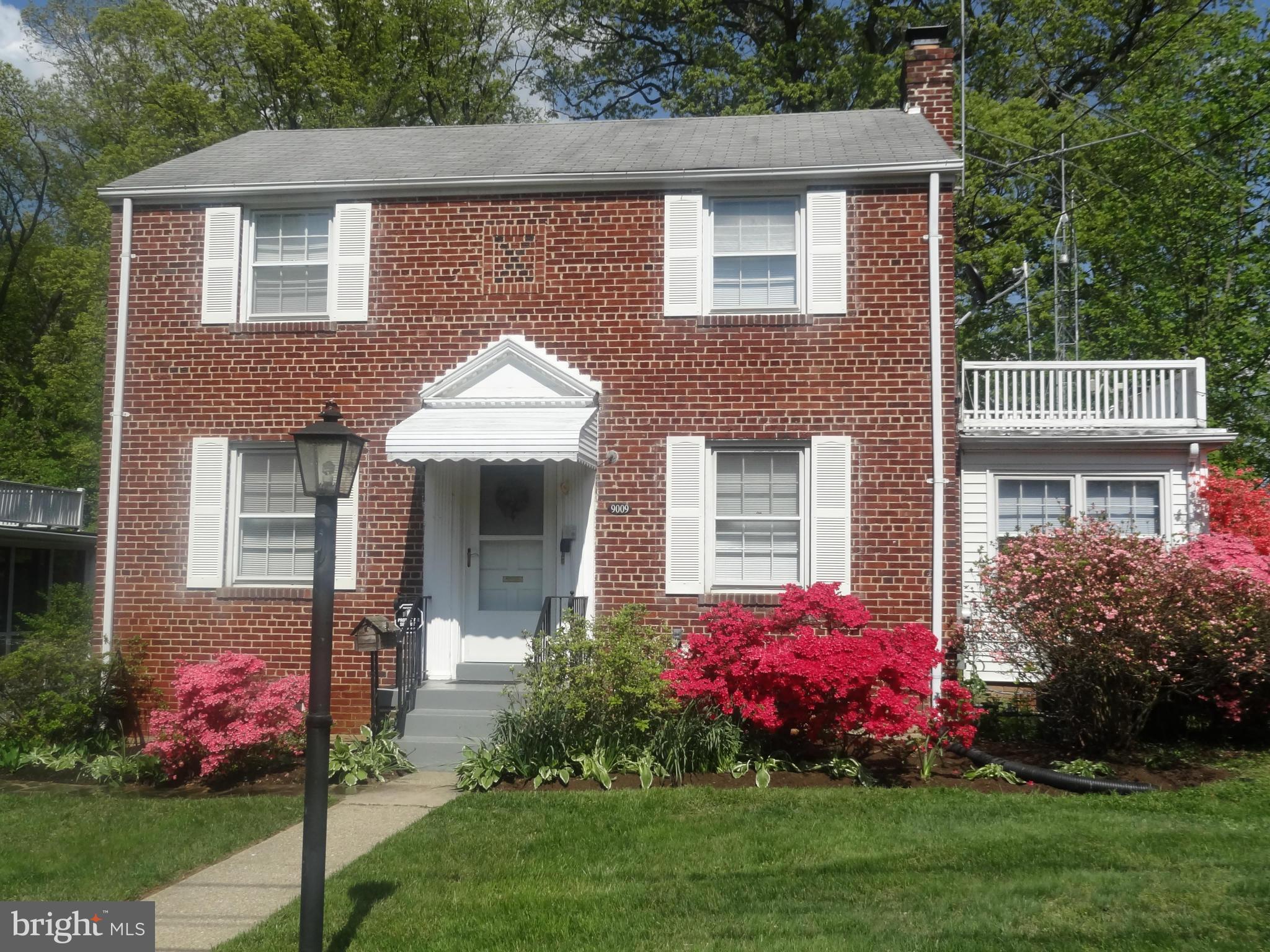 a front view of house and yard with beautiful flowers and green space