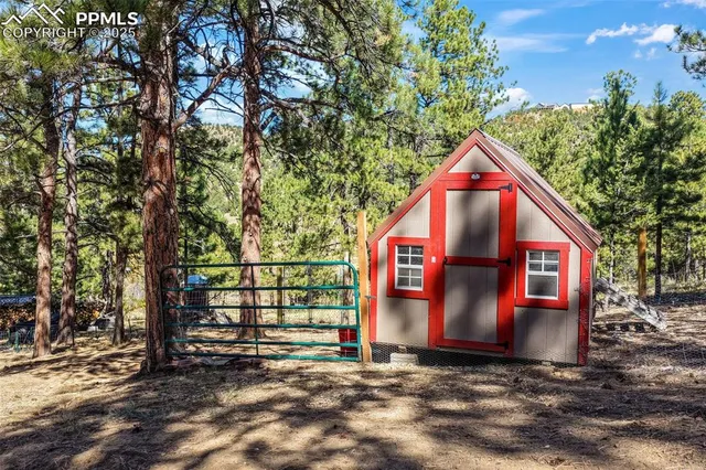 a view of a house with large tree and wooden fence