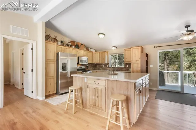 a open kitchen with stainless steel appliances granite countertop a white stove top oven a dining table and chairs with wooden floor