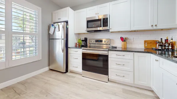 a kitchen with granite countertop white cabinets stainless steel appliances and sink
