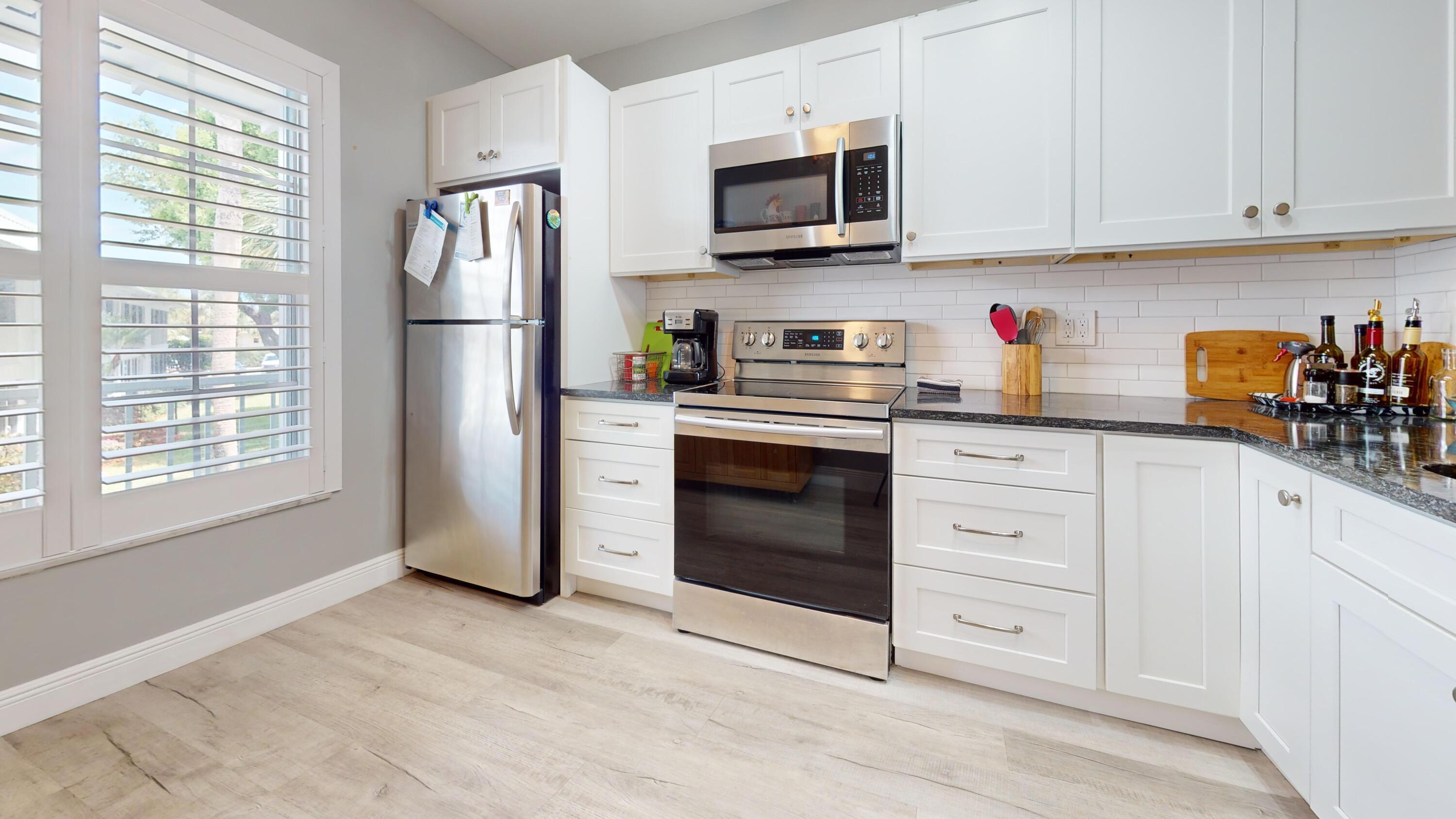 1856 Southwest Palm City Road, Unit 203 Stuart, FL 34994 - Photo 14 of 22 a kitchen with granite countertop white cabinets stainless steel appliances and sink