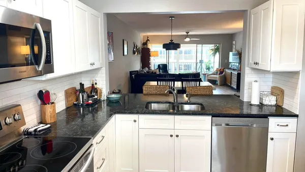 a kitchen with stainless steel appliances granite countertop a sink dishwasher and white cabinets with wooden floor