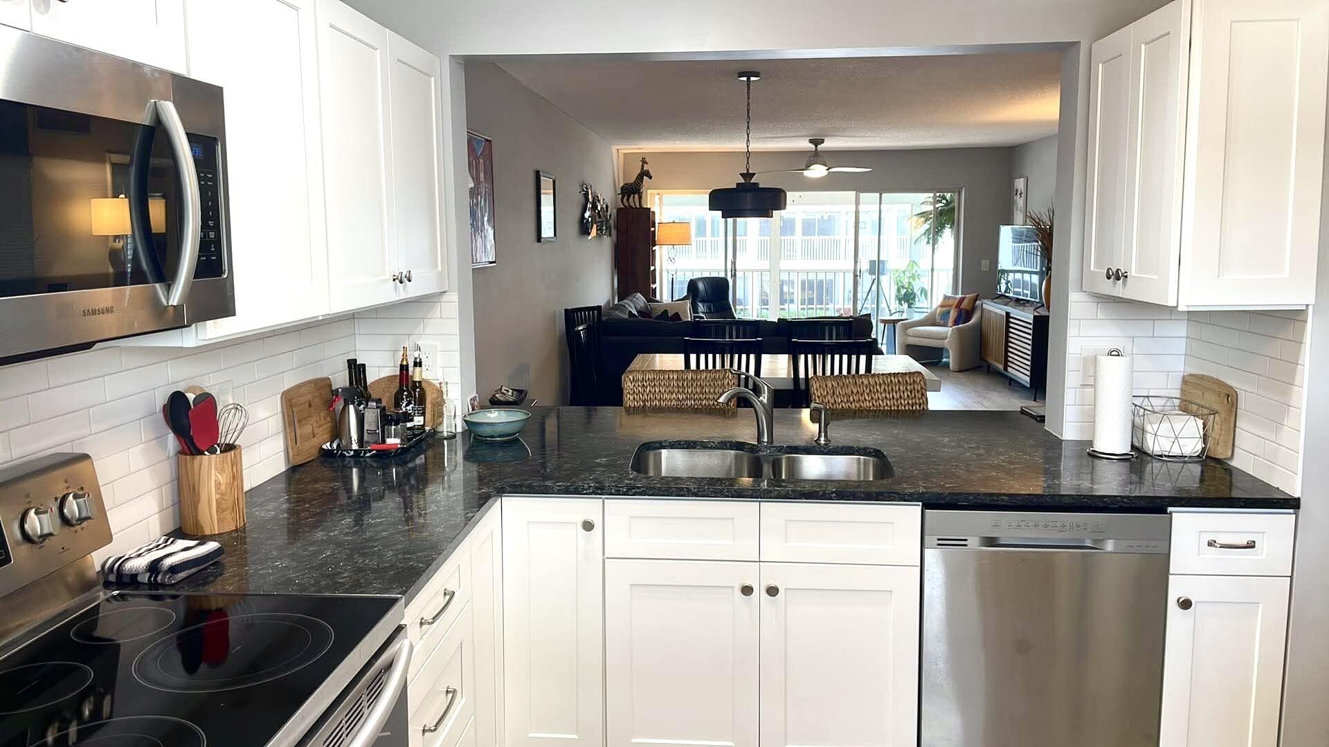 1856 Southwest Palm City Road, Unit 203 Stuart, FL 34994 - Photo 15 of 22 a kitchen with stainless steel appliances granite countertop a sink dishwasher and white cabinets with wooden floor