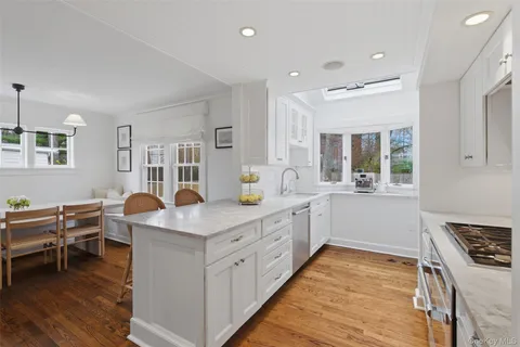 a kitchen that has a lot of white cabinets and wooden floor