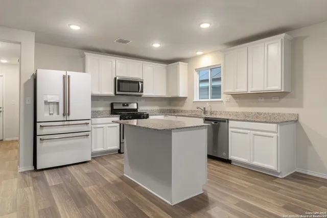 a kitchen with granite countertop a refrigerator stove top oven and sink