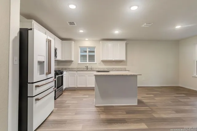 a kitchen with a refrigerator and white cabinets