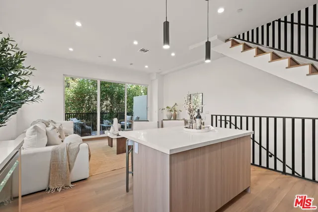 a dining hall with stainless steel appliances kitchen island a table chairs and a living room view