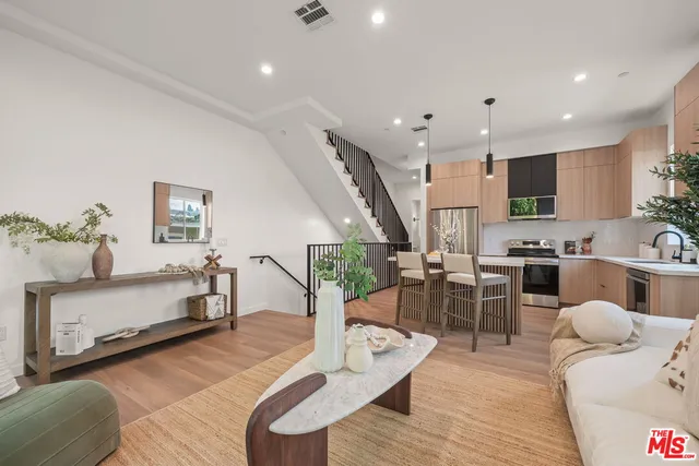 a living room with furniture kitchen view and a wooden floor