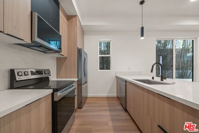 a view of kitchen with stainless steel appliances granite countertop cabinets and wooden floor