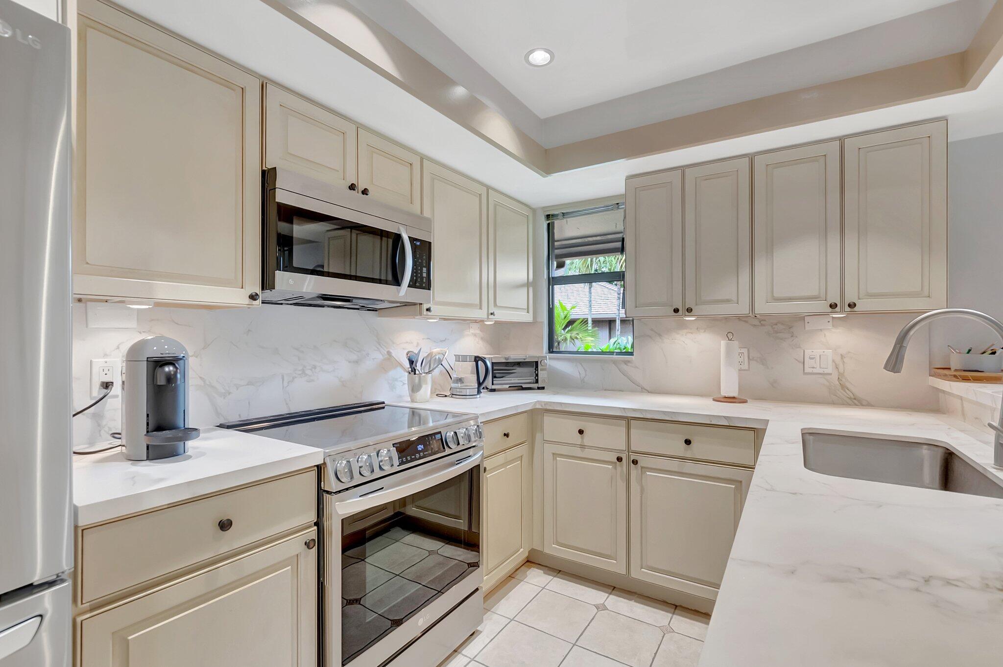 7067 Rain Forest Drive Boca Raton, FL 33434 - Photo 2 of 32 a kitchen with granite countertop white cabinets and white appliances