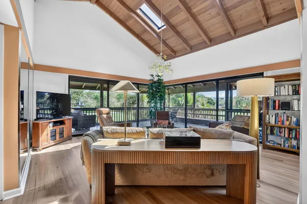 a living room with furniture a flat screen tv and floor to ceiling windows