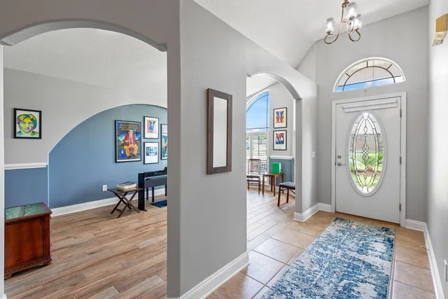 a view of a livingroom with furniture a bookshelf a chandelier and wooden floor