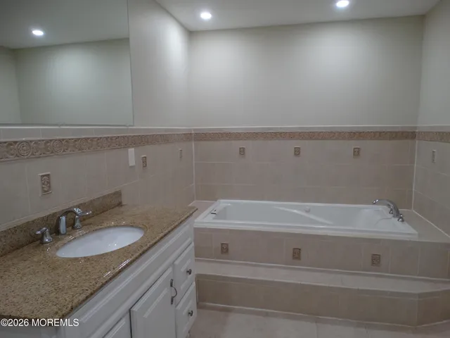 a bathroom with a granite countertop sink and tub