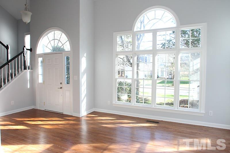 9021 Breeland Way Raleigh, NC 27613 - Photo 3 of 20 an empty room with wooden floor a chandelier