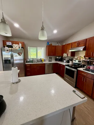 a large kitchen with stainless steel appliances a large counter top a stove and a refrigerator