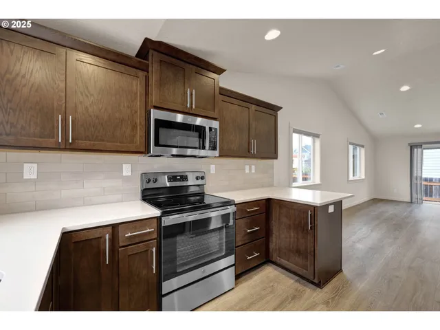 a kitchen with stainless steel appliances granite countertop a stove a sink and a microwave