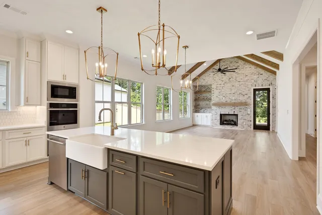 a view of large kitchen with stainless steel appliances granite countertop a sink and cabinets