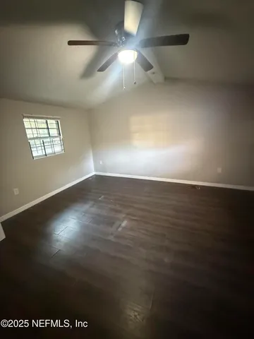 a view of an empty room with window and chandelier fan